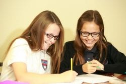 Two students share a happy laugh while working on schoolwork