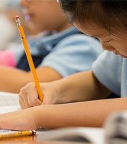 A young lady writes in her workbook in class