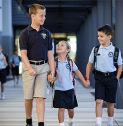 An older student holds a younger students hand