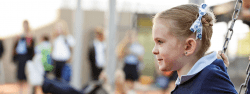 A girl swings in the playground while ignoring everyone around her