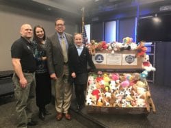 Academy personnel standing next to a large basket of stuffed animals