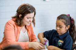 Teacher and young student cutting paper