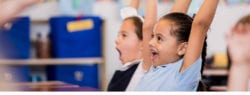 Young girls raising hands in class