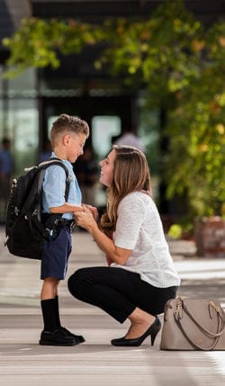 Mom says goodbye to her son on the first day of school.