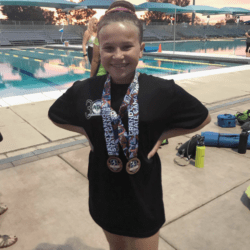 girl standing outside of swimming pool wearing medals