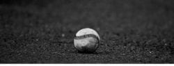 black and white photo of a baseball on the ground