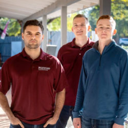 3 veritas prep alumni standing on porch