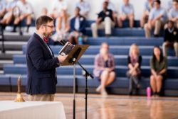 male teacher giving speech at microphone