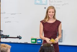 female teacher in a red dress at white board