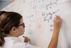 girl at whiteboard doing math