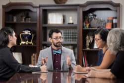 Professionals sit at a wooden table and converse.