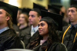 Close up of a graduate with additional graduates in the background