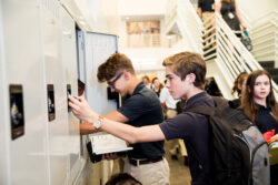 2 students at a row of lockers in a busy hall