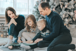 Family reading in front of Christmas Tree