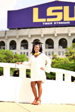 Ms. Corelus in graduation cap in from of LSU stadium