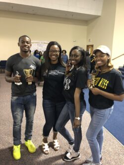 Ms. Corelus with three students holding trophies