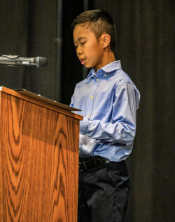 Student giving speech on a virtue at 5th grade promotion ceremony