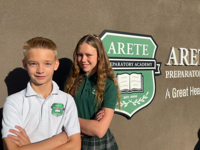 students posing next to Arete Prep signage