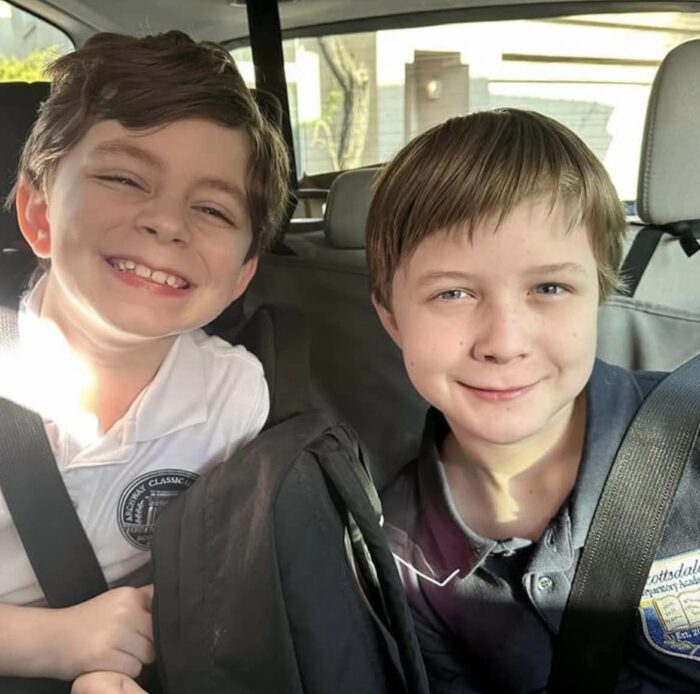 two students in the backseat of a car being driven to their first day of school