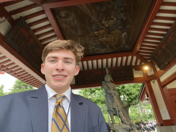 Student in front of traditional Japanese painting above a relic statue