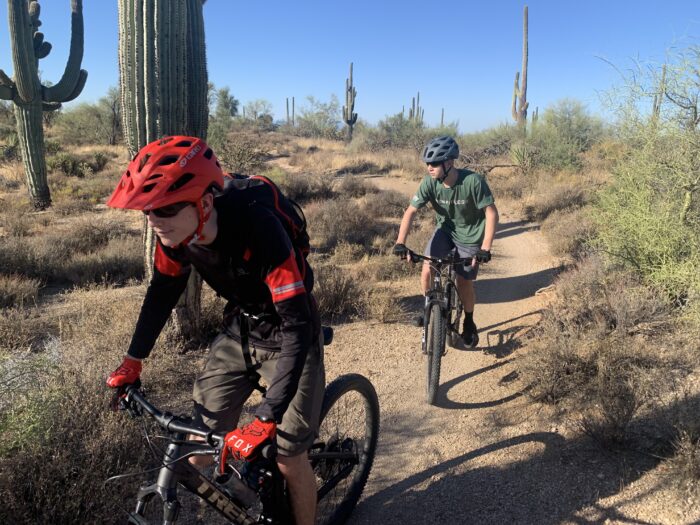 Students mountain bike riding through desert terrain.