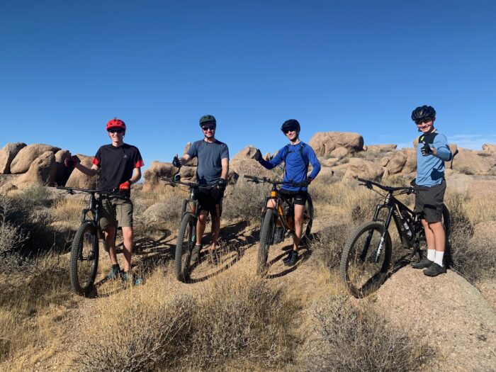 Student mountain bike riding through desert terrain.