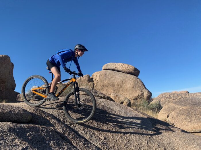 Student mountain bike riding through desert terrain.