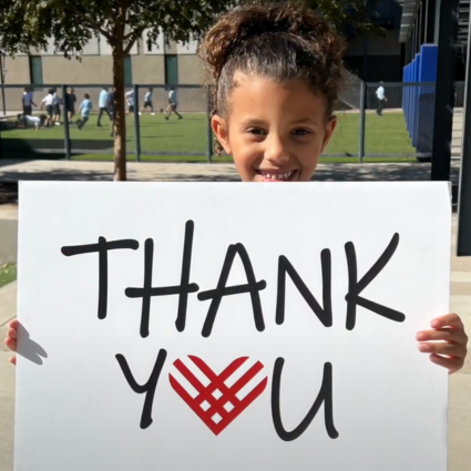 girl holding a Thank You sign for Giving Tuesday