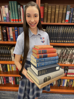 Anthem student holding books that she collected for Anthem libraries.