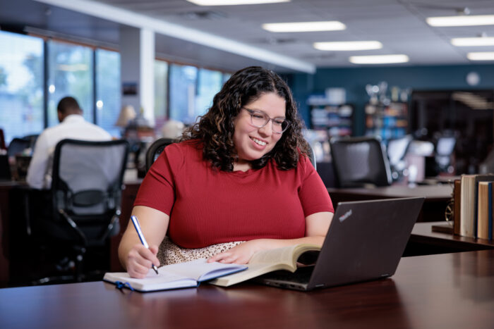 Woman at a desk with laptop and a notebook