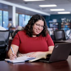 Woman at a desk with laptop and a notebook