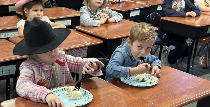 Cicero students dressed like pioneers eating cake for Arizona's birthday.