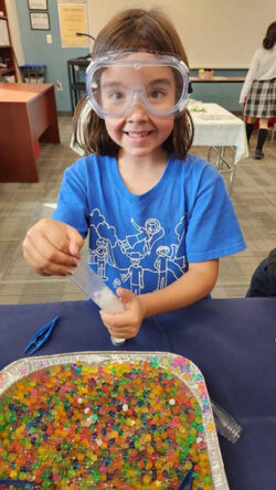 Summer camp student with goggles at summer camp table