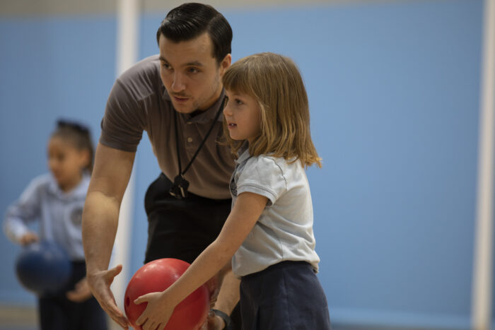 A coach with a student throwing a ball