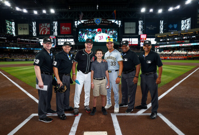 Student on the home plate with coaches and umpires at Chase Field.