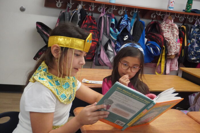 Student dressed as literary character reading to a younger student