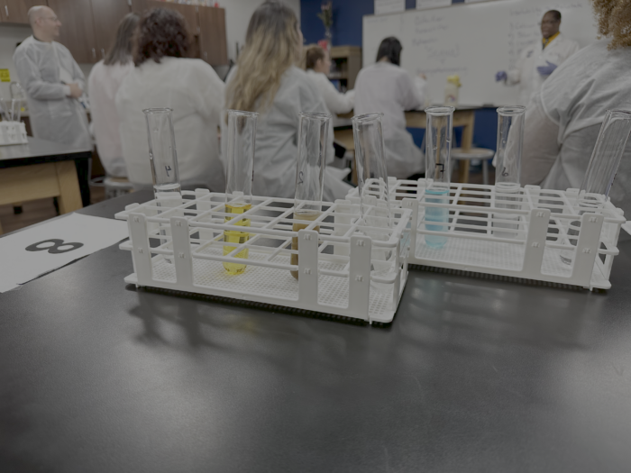 Close up of science lab tools with teacher and students in the background.