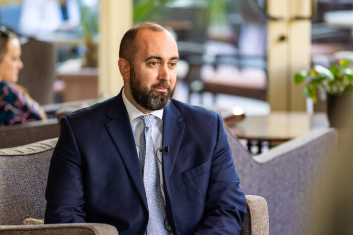 A man in a suit sitting in a lobby.