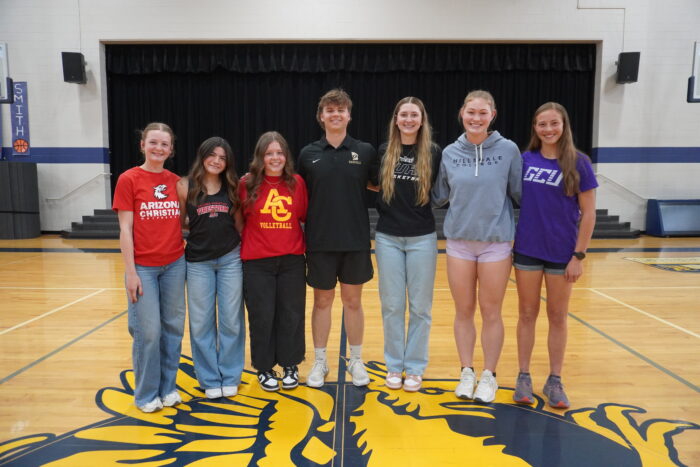 Seven thletes posing together on a basketball court