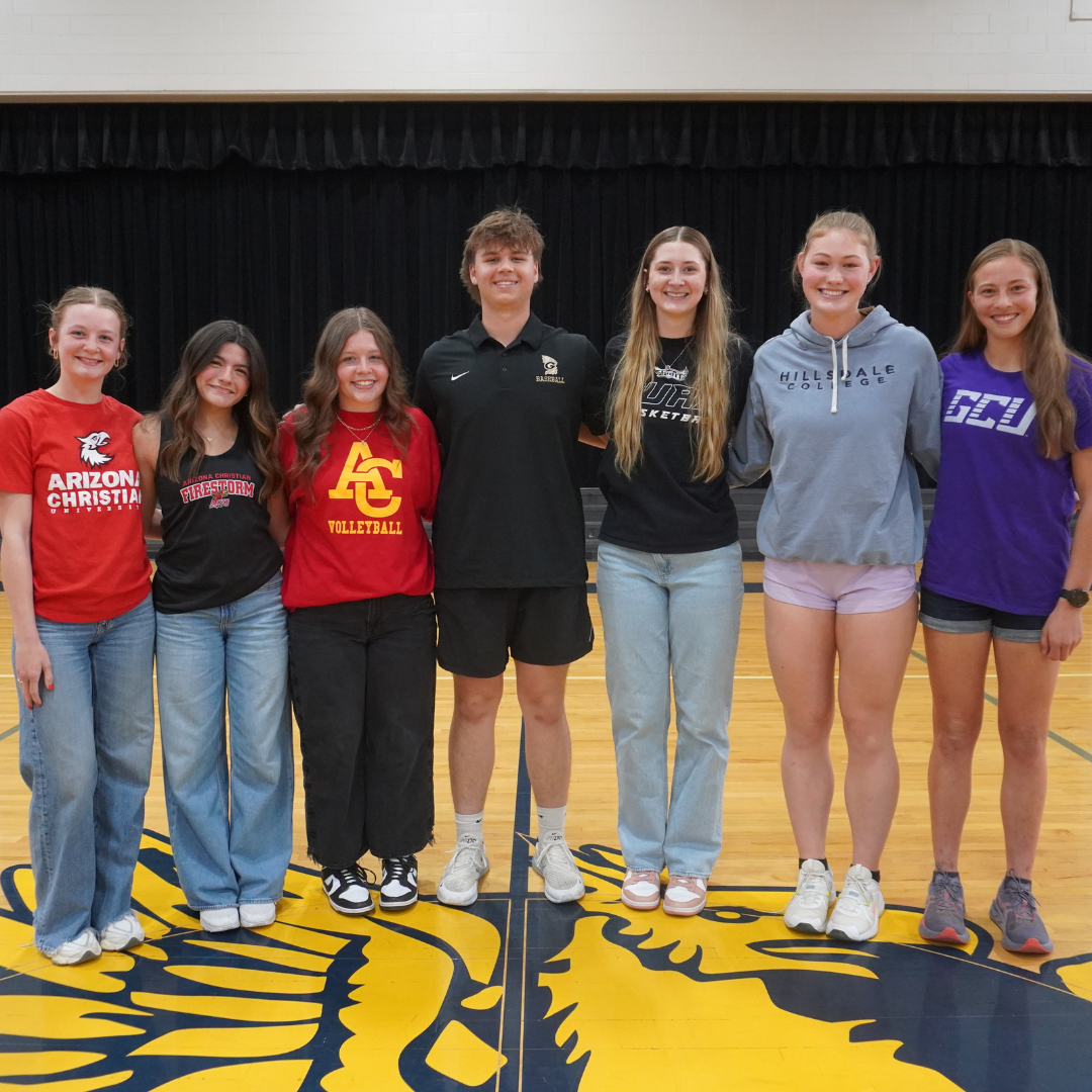 Seven thletes posing together on a basketball court