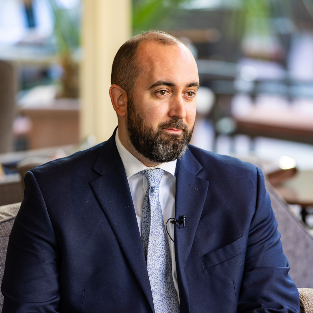 A man in a suit sitting in a lobby.