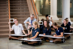 A group of students sitting on the floor working on a pencil sketch projects.