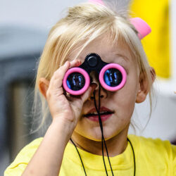 Girl looking through a pair of binoculars.