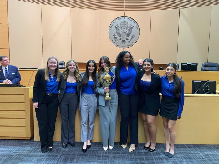students posing in a courtroom with a trophy