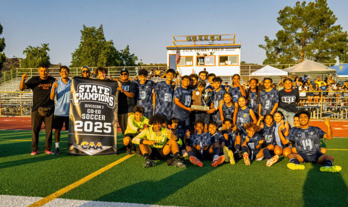 Soccer team picture with state champions banner and trophy