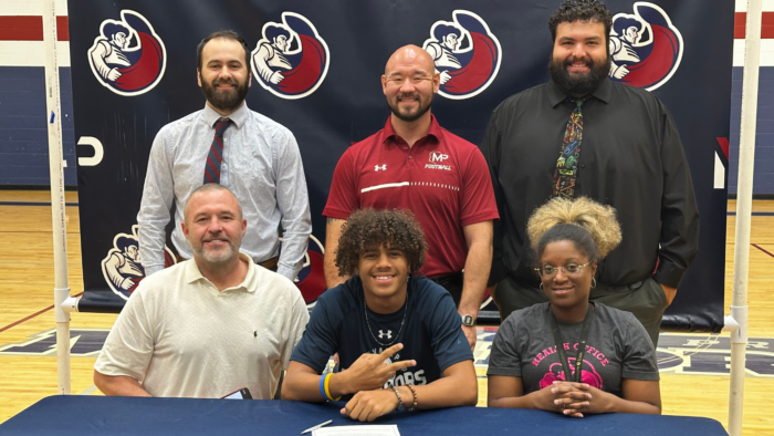 Senior posing with parents and coaches at table