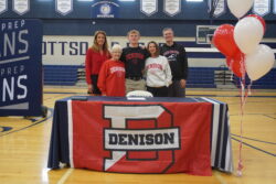 Student athlete posing with his family and Denison University banner