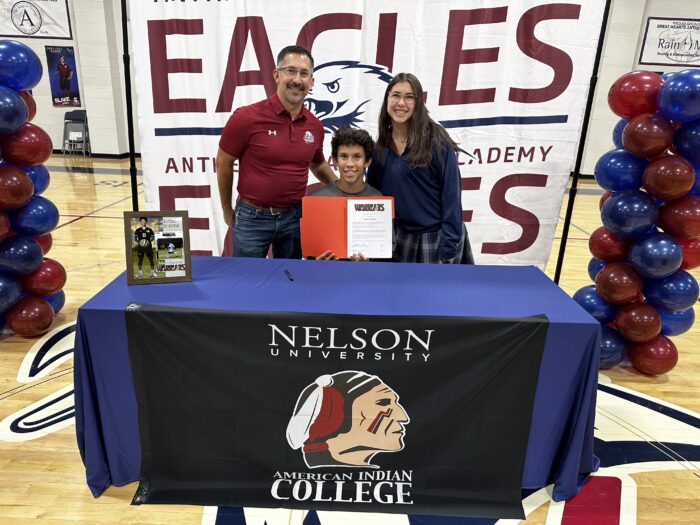 Student with family behind a table with Nelson University logo