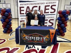 Student with family behind a table with Nelson University logo