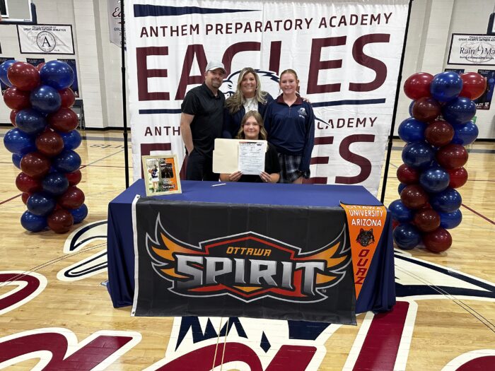 Student with family behind a table with Nelson University logo